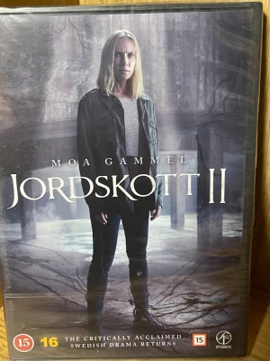 Jordskott II DVD-box - Jordskott II är en svensk dramaserie på DVD med mörkt omslag och mystisk stämning. Serien handlar om Eva Thörnblad och utspelar sig i Stockholm. Boxen har tydliga åldersmärkningar och är producerad av Palladium och ITV Studios. Perfekt för dig som gillar spänning och nordisk thriller.