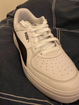 Vita och svarta sneakers från Puma - Stilrena sneakers från Puma i vitt med svarta detaljer och klassisk logga på sidan. Kom små på mig