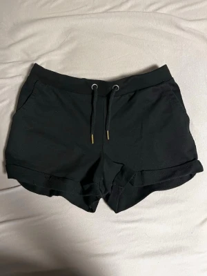 Svarta shorts med snörning - Svarta shorts i mjukt bomullsmaterial med snörning i midjan och uppvikta benslut. Perfekta för sommaren och har en avslappnad passform med fickor på sidorna.