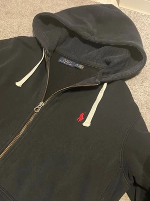 Hoodie Polo Ralph Lauren  - Hoodie Polo Ralph Lauren 🧥  This is a dark hoodie from Polo Ralph Lauren, featuring a red embroidered logo. It appears to be in very good condition with no visible flaws.  ⭐️ Condition: 9/10 🎲 Size: L/G 📦 Fast and careful shipping