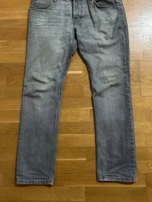 Grå raka jeans i klassisk modell - Snygga grå jeans med klassisk femficksdesign. Jeansen har en något tvättad look och är tillverkade i mjukt denimtyg. Perfekta för dig som gillar en enkel och stilren stil med storleken 33/32