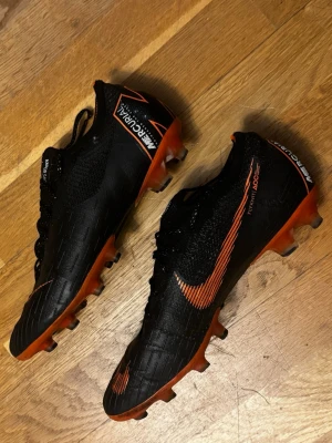 Nike Mercurial Vapor fotbollsskor - Säljer ett par svarta och orange Nike Mercurial Vapor i storlek 42. Inga synliga eller större skador på skorna så mycket bra skick på de! Skriv för frågor!
