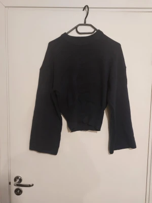 Mörkblå stickad tröja med vida ärmar - Mörkblå stickad tröja med rund hals och vida ärmar. Tillverkad i en mjuk mix av 50% viskos, 28% polyester och 22% polyamid. Perfekt för en avslappnad och trendig look.Endast testad.