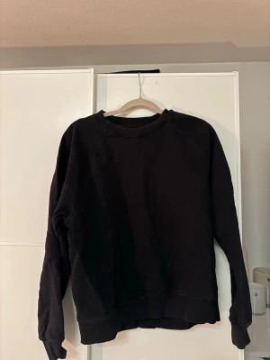 Svart sweatshirt från Cubus - En stilren svart sweatshirt från Cubus i ekologisk bomull. Tröjan har rund halsringning, långa ärmar och ribbade muddar vid ärmslut och nederkant. Perfekt för en avslappnad och enkel look.🤎