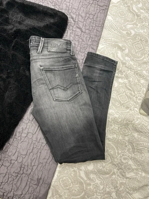 Replay Anbass grå jeans herr - Säljer ett par Replay Anbass jeans i snygg grå tvätt. Jeansen har klassisk femficksmodell, raka ben och normal passform. Tillverkade i mjuk bomullsdenim med stretch för extra komfort. Perfekta för dig som gillar stilrena och moderna jeans. Waits 28 Lenght 30. Passar dig som är 175-180 cm