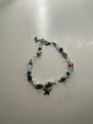 Armband - Unikt halsband med snäckor, turkosa och vita pärlor samt en silverfärgad sjöstjärneberlock. Kedjan är justerbar och smycket kan användas som både armband och fotlänk!