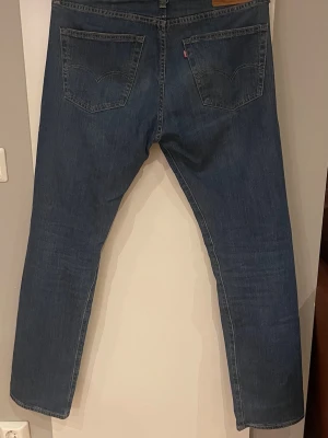 Levi's 502 blå jeans herr - Klassiska blå Levi's 502 jeans med raka ben och normal passform. Jeansen har fem fickor, tydliga sömmar och den ikoniska läderpatchen bak i midjan. Tillverkade i slitstarkt bomullsjeansmaterial, perfekta för en avslappnad stil. Hör av er vid minsta fråga 🤗🤗