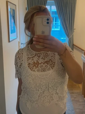 Vit spetsblus med blommigt mönster - Säljer en vit blus med vackert blommigt spetsmönster. Blusen är kortärmad och har rund halsringning samt fina detaljer både fram och bak. Linnet ingår inte, från bikbok i storlek M ☺️