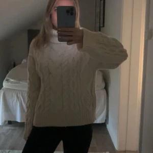 Vit kabelstickad polotröja - Mysig vit kabelstickad polotröja med breda ärmar och ribbade muddar. Perfekt för kalla dagar och ger en trendig oversized look. Tröjan har ett klassiskt flätmönster och hög krage. storlek S❤️