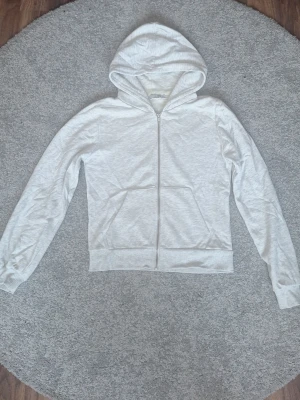 Ljusgrå zip hoodie från lager 157 - Ljusgrå hoodie med dragkedja från lager 157. Klassisk modell med huva och två stora fickor framtill. Tillverkad i mjukt bomullsmaterial och har ribbade muddar vid ärmslut och nederkant. Perfekt för en avslappnad och stilren look. Inte använd så mycket! 🩷