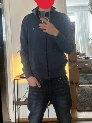 Blå ziptröja från Polo Ralph Lauren stl M men känns mer som S - Snygg blå ziptröja från Polo Ralph Lauren med klassisk vit logga på bröstet. Tröjan har hög krage, hel dragkedja och ribbade muddar. Perfekt för en avslappnad men stilren look. Materialet känns mjukt och bekvämt.