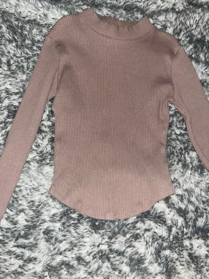 Ribbad brun stickad tröja Gina Tricot - Ribbstickad brun långärmad tröja från Gina Tricot med hög hals. Tröjan har en slim passform och är perfekt att styla med jeans eller kjol. Enkel och stilren design som funkar till många olika looks. Passar perfekt som Xs och S!