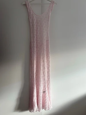 Ljusrosa långklänning i spets - Superfin långklänning i ljusrosa spets med ärmlös design och rundad urringning. Klänningen har en romantisk känsla och är perfekt för sommarens alla tillfällen. Tunn och luftig med vacker spetsdetalj över hela plagget.