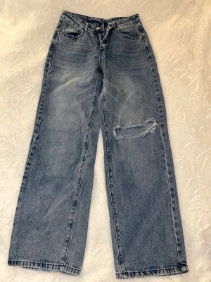 Mörkblå wide jeans med slitning  - Säljer ett par mörkblå jeans med breda ben och en stor sliten detalj på ena låret. Jeansen har klassisk femficksdesign, hög midja och är tillverkade i ett robust denimtyg. Från Shein, strl W27. 