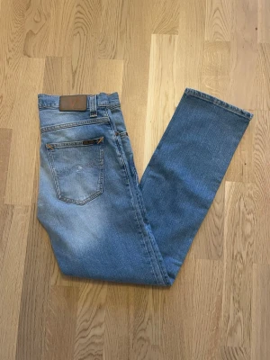 Blå Nudie jeans Grim Tim W30 L32 - Jag säljer dom här feta Nudie jeansen i den populära modellen Grim Tim. Storleken är W30 L32. De är inte använda mycket alls och har inga defekter. Detta är ett riktigt kap med tanke på att dessa kostar 1599kr nya. Tveka inte att höra av er!                                                                                   Mått: Längd=101cm. Midja=41cm