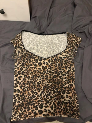 Leopardmönstrad topp - Snygg leopardmönstrad mesh topp med korta ärmar och djup v-ringning. Tunn och stretchig i materialet. Svarta detaljer längs halsringningen ger extra kontrast. Säljer den då den inte används ❣️