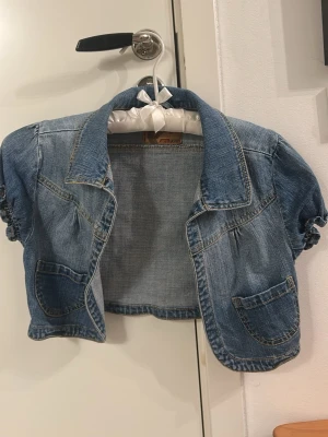 Kort jeansjacka med puffärmar - Kort jeansjacka i blå denim med puffärmar och två framfickor. Bolero. 