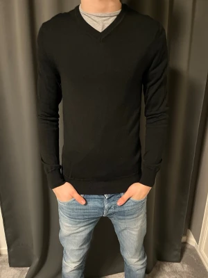 Ted Bernhardtz v ringad tröja - Klassisk svart V-ringad tröja 100% merinoull med lång ärm och ribbade muddar. Enkel och stilren design som passar till det mesta. Tillverkad i mjukt material som känns skönt mot huden. Perfekt att bära över en t-shirt eller skjorta. Det är ett litet hål under armen men det går att sy. Nypris 899kr säljs för 350kr! Pris kan diskuteras! 