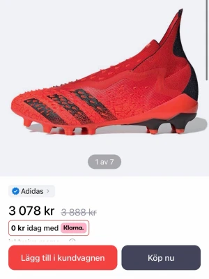 Adidas Predator fotbollsskor - Säljer ett par röda adidas Predator fotbollsskor med svart detaljering och stickad ovandel. Skorna har en strumpliknande passform utan snörning och är designade för maximalt grepp på planen. Perfekta för dig som vill dominera matchen med stil.