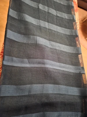 Öljettgardiner - Säljer ett par eleganta, halvtransparenta gardiner i en djup mörkblå ton. Gardinerna har ett stilrent randigt mönster med en subtil fiskbensväv (herringbone) som ger rummet en modern och ombonad känsla.  ​Tack vare öljetterna är de extremt lätta att hänga upp och ger ett snyggt, naturligt fall direkt på stången. Materialet släpper igenom ett behagligt ljus samtidigt som det dämpar direkt insyn.  Gardinlängder mått: Ca 231cm långa och 140cm bred.  Gardinkappa mått: Ca 253cm lång och 44cm bred