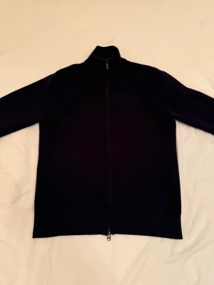 Bläck Zip Tröja - Snygg marinblå ziptröja med hög krage och hel dragkedja framtill. Tröjan har en minimalistisk design och ribbade muddar vid ärmslut och nederkant. Perfekt att slänga på sig över en t-shirt för en clean look.