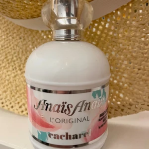 Anaïs Anaïs L'Original parfym - Anaïs Anaïs L'Original från Cacharel är en klassisk parfym i en vit rund flaska med silverfärgad kork och romantiska blommiga detaljer på etiketten. Doften är feminin och tidlös, perfekt för dig som gillar eleganta och fräscha parfymer. Den är endast testad en gång. Nypris 900kr