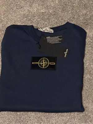 Stone Island sweater (M) Ny-oanvänd  - Säljer en helt ny och oanvänd Stone Island sweater i storlek M. Klassisk och stilren design med Stone Islands ikoniska kompassmärke på ärmen. Tröjan är tillverkad i hög kvalitet med bekvämt och slitstarkt material – perfekt för både vardag och en mer exklusiv streetwear-look. 🔹 Märke: Stone Island 🔹 Plagg: Sweater 🔹 Storlek: M 🔹 Skick: Helt ny / oanvänd 🔹 Passform: Klassisk Nypris är högt – perfekt tillfälle att göra ett riktigt fynd. Hör av dig vid frågor eller om du vill ha fl