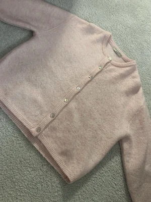 Ljusrosa kofta med knappar - Söt ljusrosa kofta från Gina tricot med rund halsringning och silvriga knappar framtill. Koftan är stickad i ett mjukt material och har ribbade muddar vid ärmslut och nederkant. Perfekt att slänga på sig över en topp.