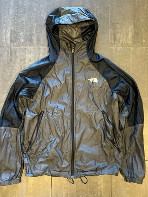 The north face jacka - En the north face windbreaker i väldigt bra skick och färgen grå/blå ish. Storlek L men justerbara band både i midja och uppe vid luvan. Tveka inte att höra av er med frågor och fundering och kolla gärna in mina andra annonser så kan vi säkert fixa ett schysst paketpris🤩🤩