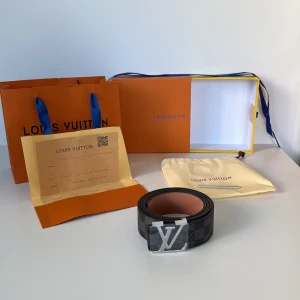 L och V Damier Graphite bälte - Snyggt  bälte i klassiskt Damier Graphite-mönster med svart och grå ruta. Bältet har en stor ogga i silvermetall som spänne och är gjort i exklusivt skinn. Kommer med originalbox, dustbag och kvitto.
