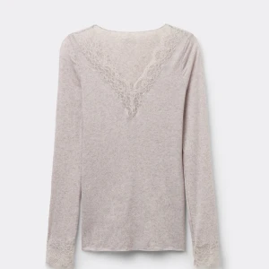 Beige långärmad topp med spetsdetaljer - Supersöt beige långärmad topp med v-ringning och fina spetsdetaljer både vid halsen och ärmsluten. Mjuk och tunn känsla i materialet! Storlek M men sitter som S.                                                               OBS! Tröjan har ett litet hål strax vid halsen (läggs ej märke till). 