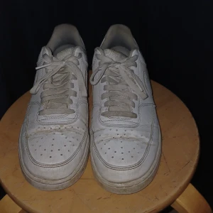 Nike Air Force 1 vita sneakers 42 - Klassiska vita Nike Air Force 1 sneakers i low-modell. Skorna har snörning, rund tå och platt sula. Tillverkade i skinn med diskreta detaljer och Nike-logga bak. Perfekta för dig som gillar en clean och tidlös look.