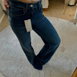 Blå wide jeans från Zara, storlek 34 - Snygga mörkblå jeans från Zara i storlek 34. Modellen har en wide passform med medelhög midja. Jättebekväma och snygg i både färg och passform. Prislappen sitter kvar, alltså aldrig använda. Hör gärna av er vid frågor osv 💓 obs köparen står för frakt 