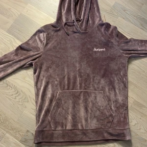 Ljuslila sammetshoodie från FB Sister - Mysig ljuslila hoodie i sammet från FB Sister med broderad text 'Awesome' på bröstet. Tröjan har huva med snörning, magficka och långa ärmar. Perfekt för dig som gillar mjuka och sköna plagg med lite extra stil.