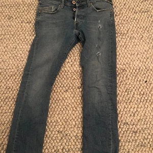 Replay jeans  - Replays jeans med små slitningar och små röda detaljer vilket gör jeansen riktigt feta! Priset går att diskutera! OBS ett litet hål under knapparna i skrevet men det märks knappt! 