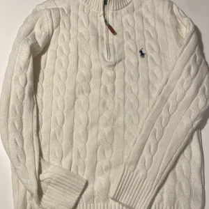 Vit stickad polotröja från Polo Ralph Lauren - Endast testad. Säljer en vit polotröja i storlek M från Polo Ralph Lauren med klassiskt kabelstickat mönster och quarter zip framtill. Tröjan har lång ärm, ribbade muddar och den ikoniska broderade loggan på bröstet. Perfekt för dig som gillar stilrena och tidlösa plagg. QR-koden är lite skum men det är såklart inget som märks. Priset är ej hugget i sten.