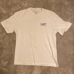 Vit t-shirt från H&M - Vit t-shirt från H&M med relaxed fit. Svampmotiv i blått och orange på ryggen. Tillverkad i 100% bomull. Är öppen för ett lägre pris vid snabb affär. Om ni har några frågor skriv gärna!