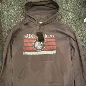 Saint Laurent hoodie  - Tja säljer denna feta hoodie, den är i topp skick och köpt på plick så kan ej garantera äkthet, där av priset. Storleken är L men den sitter som M/L, vid snabb affär kan jag gå ner i pris! Tveka inte att ställa frågor. 