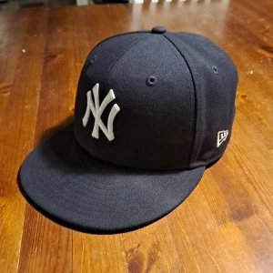 New Era Yankees keps 59FIFTY svart - Snygg svart New Era 59FIFTY keps med klassiskt New York Yankees logga. Kepsen har platt skärm, broderad MLB-logga bak och texten 'PREDATORN' på sidan. Tillverkad i bomull och polyester. KAN GÅ LÄGRE I PRIS!