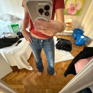 Blå bootcut jeans låg midja - Säljer ett par klassiska blå jeans med bootcut och låg midja. Jeansen har en snygg tvättad look, fem fickor och bälteshällor. Perfekta för dig som gillar en avslappnad men ändå trendig stil. Materialet är jeans och passformen är normal.