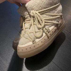Beige inukii med guld detaljer  - Super fina vinter skor som värmer och skyddar från vatten. Storlek 40 men passar mig bra som bör 38 i vanliga fall. Storleken är väldigt passande och passar 38-40 🥰  Köpta för 4000kr från Inuikii själva, under februari 2025. Alltså hyfsat nya 💕  Sparsamt använda men de är använda 💓  Tecken på användning syns bara lite i sulan, inga andra stora defekter !