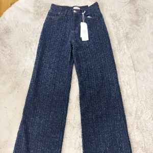 Blå mönstrade wide jeans från Ginatricot  - Säljer ett par blå jeans från Ginatricot med breda ben. Modellen har klassisk femficksdesign, high waist och raka sömmar. Materialet är jeans med ett unikt mönster, vilket ger en unik look. Perfekt för dig som vill sticka ut.