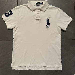 Big pony Pikétröja från Ralph Lauren - Vit (Herr L/M - Riktigt fin pikétröja från Ralph Lauren. Tröjan är i gott skick men har fått ett minihål (se bild) som knappt syns, storlek L men passar även M. Nypris ligger runt ca 2300kr