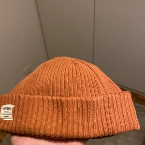 Rostbrun  mössa från Upfront - Rostbrun ribbstickad mössa från Upfront, modell Bridge Beanie. One size. Tillverkad av 97% bomull och 3% spandex. Är öppen för ett lägre pris vid snabb affär. Om ni har några frågor skriv gärna!