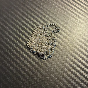 Klassisk silverfärgad halskedja - En stilren halskedja i silverfärg med diskret, tätt länkad design. Kedjan har ett smidigt lås och passar perfekt för att bära ensam eller med ett hänge. Enkel och tidlös look som funkar till många stilar.