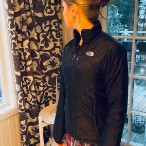 Svart  jacka från The North Face - Svart lättviktsjacka från The North Face. Jackan har en dragkedja framtill och två sidofickor med dragkedjor. Fint skick!