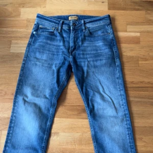 Blå jeans från Jack & Jones, 29/30 - Snygga blå jeans från Jack & Jones. Jeansen har en rak passform och normal midja, med snygga slitage. Köpta här i somras men har skaffat några nya så behöver dem inte längre. Pruta om ni känner för det. Det är bara kontakta vid frågor.