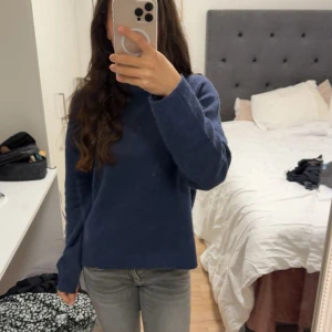 Mörkblå stickad tröja med lång ärm - Säljer en enkel och snygg mörkblå stickad tröja med rund hals och långa ärmar. Perfekt att matcha med jeans eller kjol. Tröjan har en normal passform och är mjuk och skön mot huden.