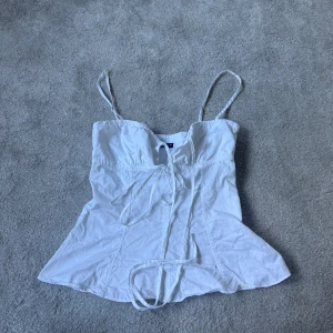 Vit korsettinspirerad linnetopp - Säljer en vit korsettinspirerad linnetopp med smala axelband och snörning framtill. 