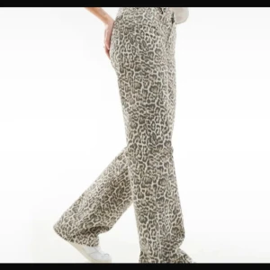 Leopardmönstrade jeans från STR - Säljer ett par snygga jeans från STR med leopardmönster i beige och bruna toner. Byxorna har hög midja, raka ben och klassisk femficksdesign. Materialet är kraftigt och känns som klassisk denim. Perfekta för dig som vill sticka ut med ett djuriskt mönster.